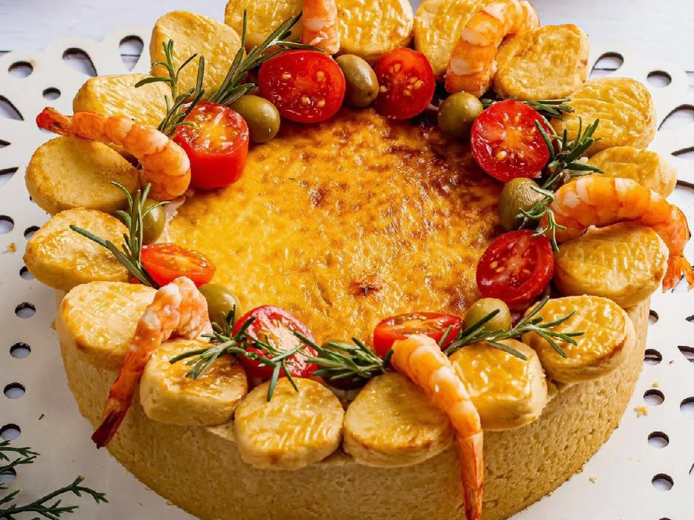 Quiche de camarão da Rôof decorada com camarões, tomates, azeitonas e alecrim